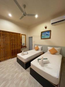 Thoddoo Retreat Grand في ثودو: غرفة فندقية بسريرين ومروحة سقف
