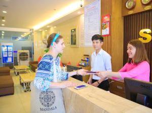 une femme remet un téléphone portable à un client à un comptoir dans l'établissement Saphia Hotel Nha Trang, à Nha Trang