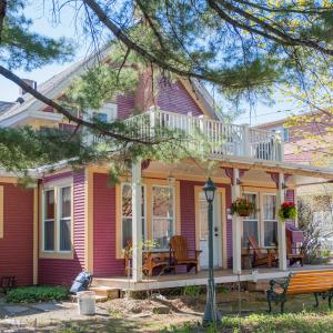a pink house with a porch and a deck at Hébergement touristique in Granby