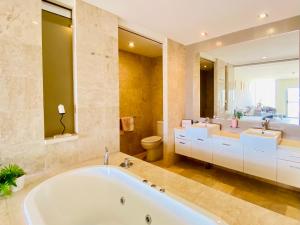 a bathroom with a tub and two sinks and a toilet at 237 Santai - Second floor studio by uHoliday in Casuarina