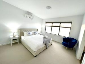 biała sypialnia z łóżkiem i niebieskim krzesłem w obiekcie Seaford Sands - Be Beside The Seaside w mieście Seaford