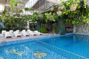 a swimming pool in a building with chairs and trees at Galina Hotel & Spa in Nha Trang