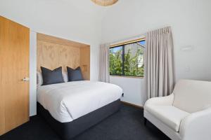 1 dormitorio con 1 cama, 1 silla y 1 ventana en The Lakehouse en Queenstown