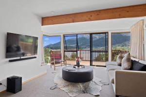 a living room with a couch and a table and a tv at The Lakehouse in Queenstown