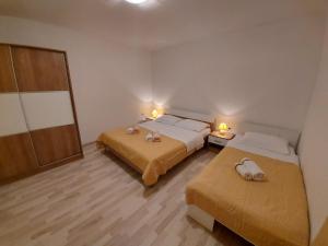 two beds in a small room with two lamps at Apartments Marija 2 in Draga Bašćanska