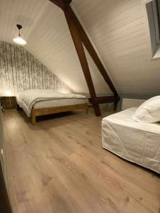 a attic bedroom with two beds and a wooden floor at Le Gîte d’Orpha in Gedinne