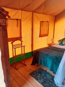 a room with a bed and a chair in a tent at Luxe safarilodgetent met boxspring bedden in Montcléra