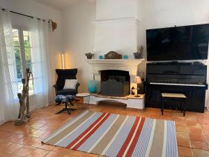 ein Wohnzimmer mit einem Klavier und einem TV in der Unterkunft Villa Petit Paradis - Gigaro in La Croix-Valmer