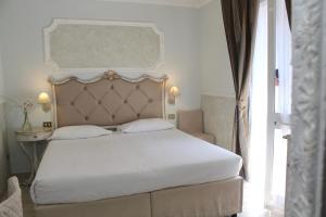 a bedroom with a white bed with a large headboard at Hotel Tahiti in Viareggio