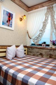ein Schlafzimmer mit einem Bett mit einer karierten Decke und einem Fenster in der Unterkunft Villa Grand Family in Rozhny