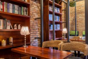 Sorgente Business Hotel في بوسان: مكتبة فيها طاولة خشبية وكراسي ورفوف كتب