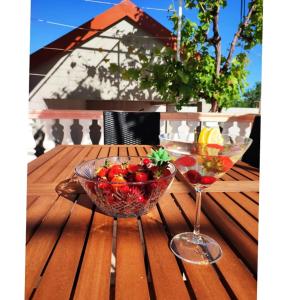 a wooden table with a bowl of fruit and a wine glass at Kuća za odmor - My Soul in Šibenik