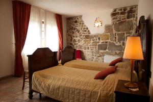 1 dormitorio con 2 camas y pared de piedra en Agriturismo La Casa Degli Ospiti, en Dolegna del Collio