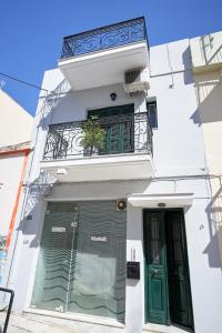 biały budynek z zielonymi drzwiami i balkonem w obiekcie Μονοκατοικία στο κέντρο με τζάκι w mieście Patras