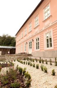 un edificio rosa con un jardín delante de él en apartmány Antik Pratterov Dom, en Banská Štiavnica