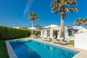 a villa with a swimming pool and palm trees at Villa Juanes in Ciutadella
