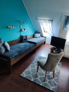 uma sala de estar com um sofá e uma cadeira e uma televisão em Blue Apartman em Makó