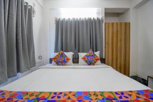 a bedroom with a large white bed with colorful pillows at FabExpress Amar Raj Villa in Kolkata