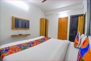 a bedroom with a white bed with a colorful blanket at FabExpress Amar Raj Villa in Kolkata
