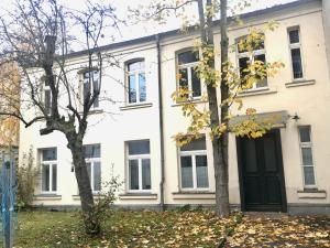 une maison blanche avec une porte noire et deux arbres dans l'établissement Wohlfühl-Oase mitten in der Stadt - Garten, Grill, Netflix und Drucker, à Leipzig