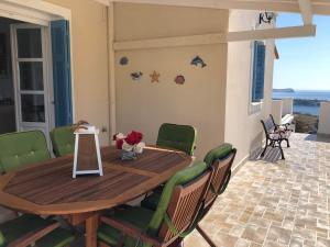 a wooden table with green chairs on a patio at BAY VIEW HOUSE in Megas Gialos - Nites