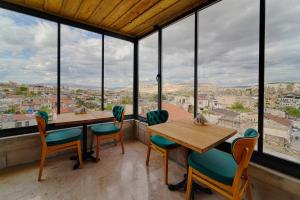 Un comedor con mesa y sillas y grandes ventanales. en Concept Cave Suites, en Göreme