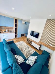 a living room with a blue couch and a kitchen at Garden Villas in Donji Štoj
