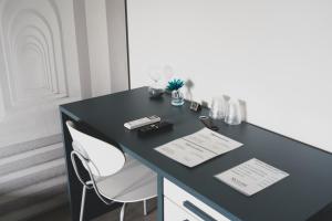 a black desk with two white chairs in a room at Skyline Rooms & Suites in Grottaminarda