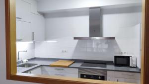 una cucina bianca con lavandino e forno a microonde di Os Reloxos II a Mondariz-Balneario