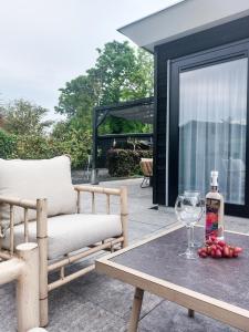 a patio with a bench and a table with a wine glass at Luxe vakantiehuis Nova met zwembad in Ouddorp