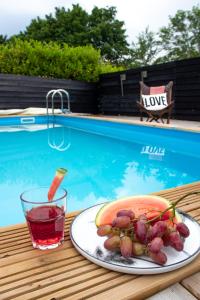 un plato de comida y una bebida junto a una piscina en Luxe vakantiehuis Nova met zwembad, en Ouddorp