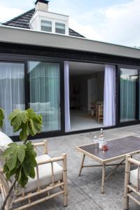 een patio met een tafel en stoelen bij Luxe vakantiehuis Nova met zwembad in Ouddorp