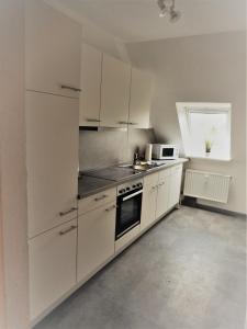 a kitchen with white cabinets and a stove top oven at Landhaus Katharina in Westerdeichstrich