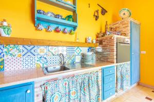 cocina con armarios azules, fregadero y paredes amarillas en Casale siculo, en Avola