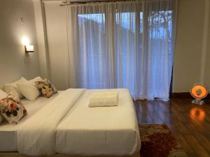 1 dormitorio con 1 cama blanca grande y ventana en Miknaon Farm Stay, en Pedong