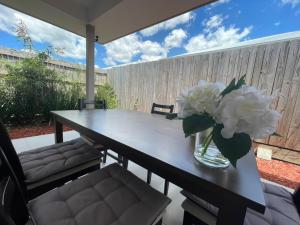 a dining room table with a vase of flowers on it at Tropical Ocean Vibe Holiday House in Strathpine in Strathpine