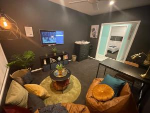 uma sala de estar com uma mesa e cadeiras e uma televisão em Tropical Ocean Vibe Holiday House in Strathpine em Strathpine