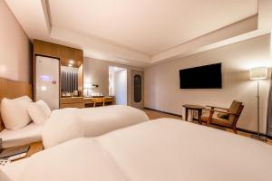 a hotel room with two beds and a flat screen tv at Hotel the Hill in Gwangju