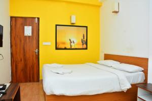 1 dormitorio con 1 cama grande y pared amarilla en FabExpress GL Classic With Bar, Porvorim, en Old Goa