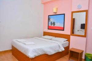 a bedroom with a bed with white sheets and a mirror at FabExpress GL Classic With Bar, Porvorim in Old Goa