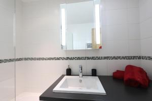 Le Schuss Tignes, appartement cosy 4 personnes في تينيِ: حمام أبيض مع حوض ومرآة