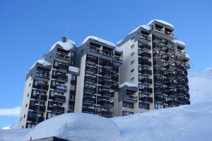 dois edifícios altos com neve na frente deles em Le Schuss Tignes, appartement cosy 4 personnes em Tignes