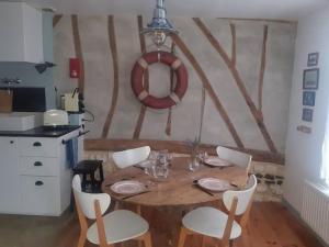 a wooden table with white chairs and a kitchen at St Elme, maison de pêcheurs, WIFI jardin in Ault