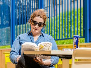 a woman sitting in a chair reading a book at ibis budget Paris Porte d'Italie Ouest in Le Kremlin-Bicêtre