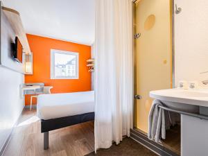 a room with a bed and a sink and a mirror at ibis budget Paris Porte d'Italie Ouest in Le Kremlin-Bicêtre
