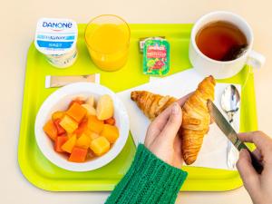 a tray with a person holding a knife and a plate of food at ibis budget Paris Porte d'Italie Ouest in Le Kremlin-Bicêtre