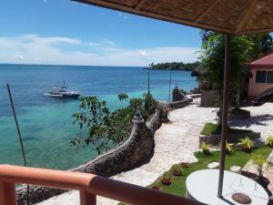 einen Balkon mit Blick auf ein Boot im Meer in der Unterkunft Sunset Vista Sea Front Guest House in Camotes Islands
