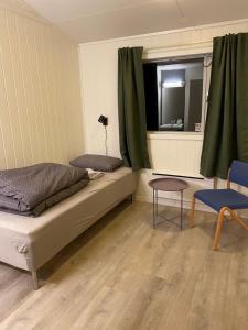 a bedroom with a bed and a window and a chair at Høgtun kulturklynge in Olsborg