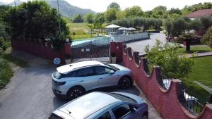 zwei Autos auf einem Parkplatz neben einem Zaun geparkt in der Unterkunft Villino Maria in Sarzana