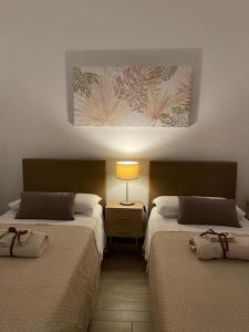 a room with two beds and a lamp on a wall at Taormina Family Apartment in Taormina
